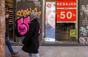 ep dos hombres pasean junto a una tienda en madrid en la que se ofertan rebajas de hasta un 50