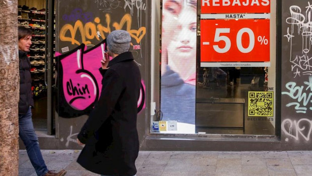 ep dos hombres pasean junto a una tienda en madrid en la que se ofertan rebajas de hasta un 50