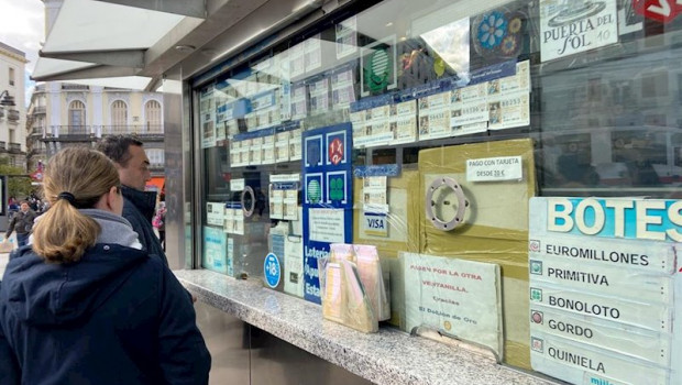 ep dos personas compran un decimo de loteria de navidad en una administracion en la plaza de puerta