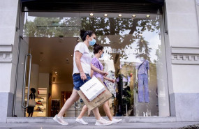 ep varias personas con mascarillas pasan al lado de la puerta de una de las tiendas fisicas de la