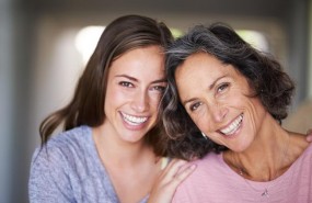 ep a laughing mother and daughter standing in their home and looking at the camera