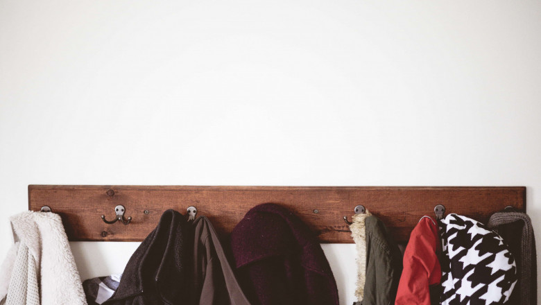 1618925118 wooden coat hanger full of coats on white wall min 