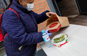 ep una mujer protegida con mascarilla y guantes de latex abre el menu infantil de telepizza en el
