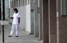ep una sanitaria con mascarilla consulta su movil en la puerta del garaje del hotel city house