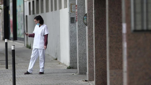 ep una sanitaria con mascarilla consulta su movil en la puerta del garaje del hotel city house