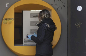 ep una mujer saca dinero con guantes en el cajero de un banco durante el primer dia laborable desde