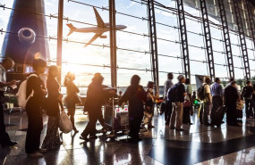 ep pasaros en un aeropuerto con un avion sobrevolando de fondo