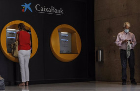 ep dos personas en los cajeros dispuestos en el edificio de la sede de caixabank en valencia