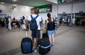 ep varias personas esperan con maletas y observan los carteles de salidas en la estacion de