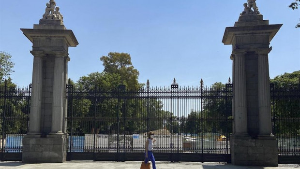 ep una mujer pasa al lado de una de las puertas del parque de el retiro