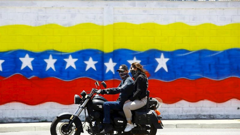 Jóvenes con mascarilla frente a una bandera de Venezuela | Juan Carlos Hernandez/ZUMA Wire/ DPA ep jovenes con mascarilla frente a una bandera de venezuela