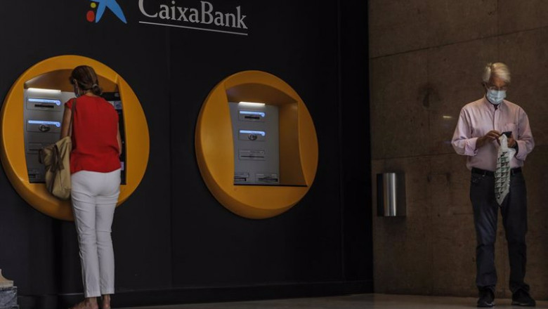 Rober Solsona - Europa Press - Archivo ep archivo dos personas en los cajeros dispuestos en el edificio de la sede de caixabank en