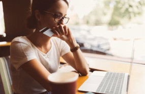 ep mujer delante de un ordenador portatil con una tarjeta bancaria en la mano