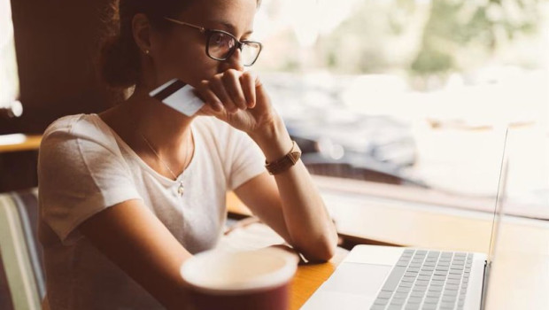 ep mujer delante de un ordenador portatil con una tarjeta bancaria en la mano